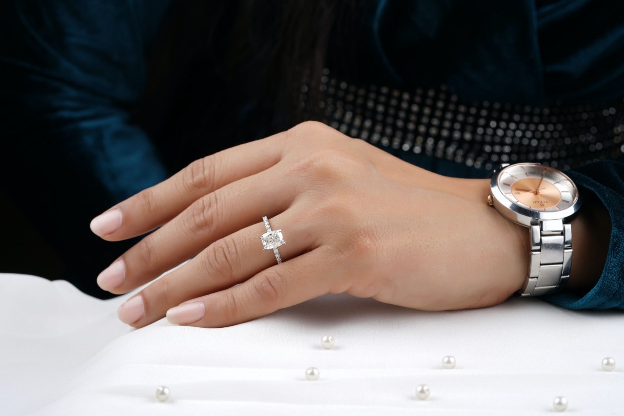 a person’s hand resting on a white surface and wearing a white gold emerald cut engagement ring a person’s hand resting on a white surface and wearing a white gold emerald cut engagement ring
