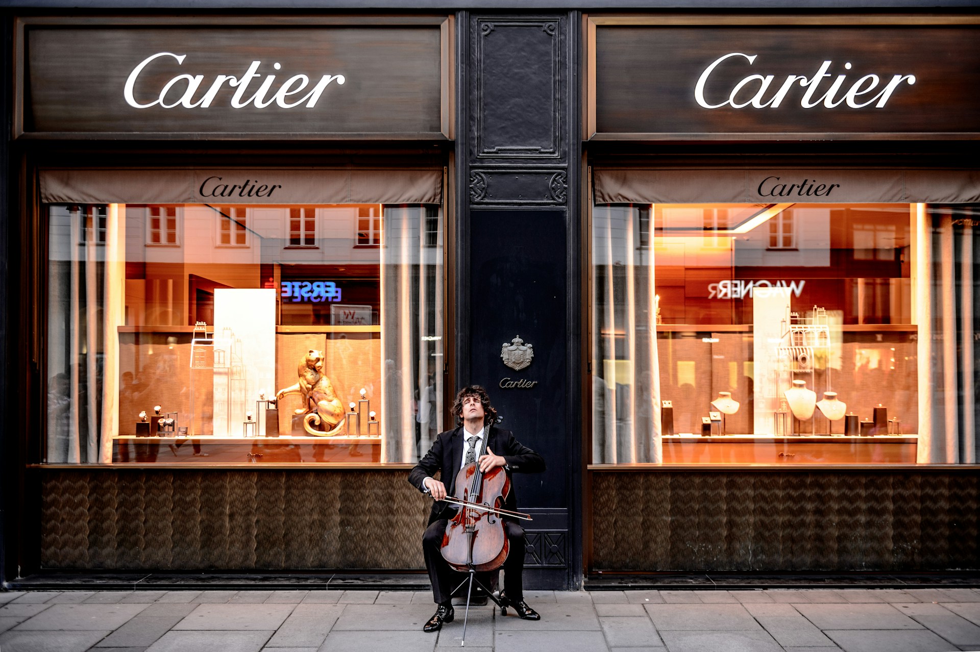 a man playing the cello sitting outside a Cartier store a man playing the cello sitting outside a Cartier store