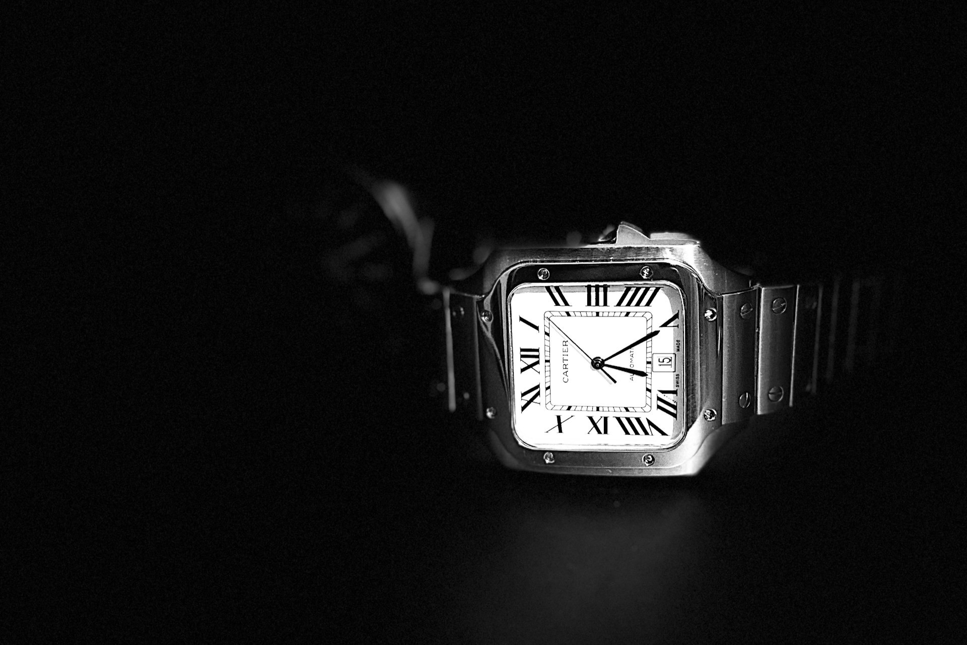 a Santos de Cartier watch on a black background a Santos de Cartier watch on a black background