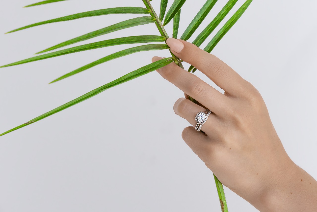 A TACORI engagement ring on the hand of a woman holding a palm frond. A TACORI engagement ring on the hand of a woman holding a palm frond.